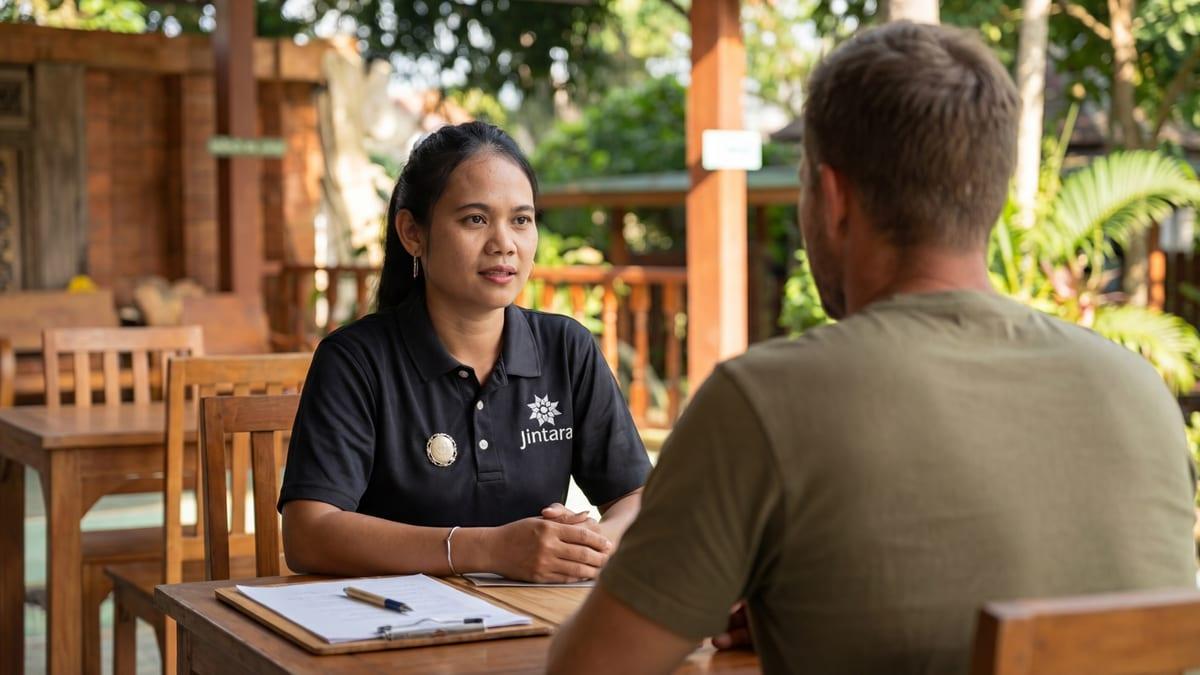 Clinical staff member in conversation with a client at an outdoor table at Jintara Rehab