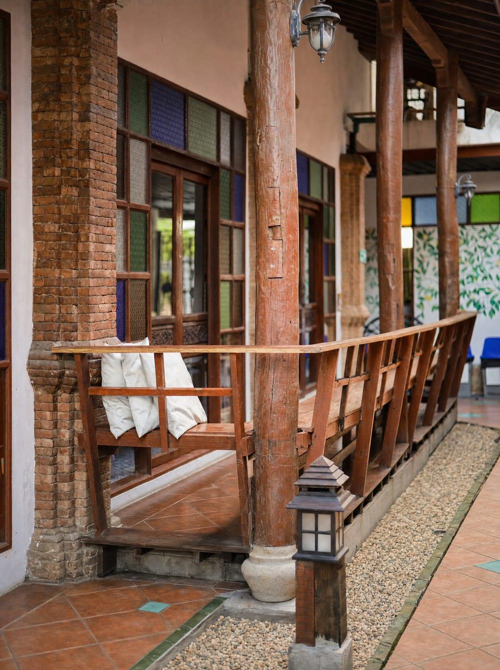 Covered garden veranda with timber bench, brick columns and stained glass at Jintara Rehab Chiang Mai