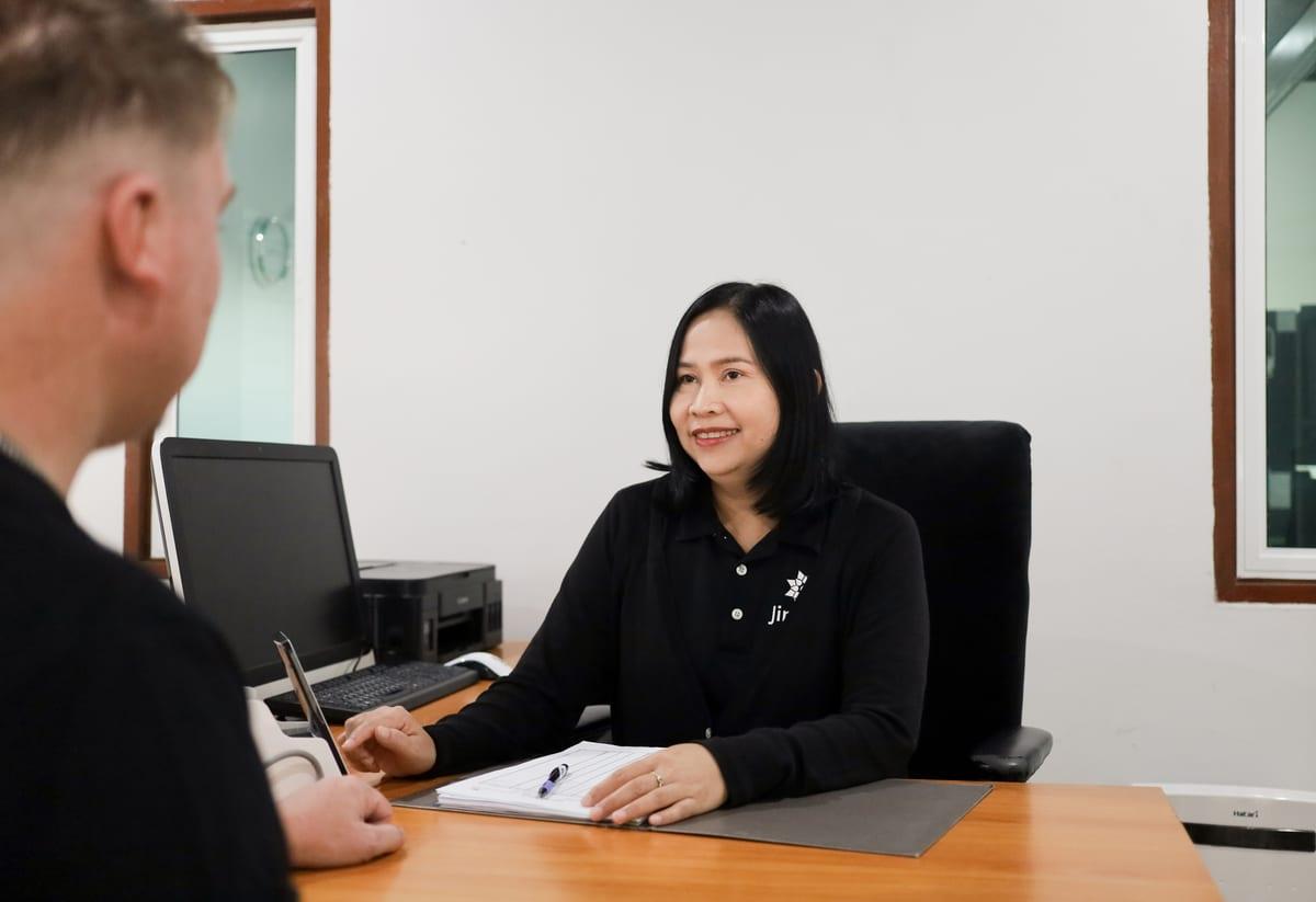 A Jintara staff member at a desk in consultation with a client at Jintara Rehab Chiang Mai