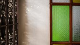 Afternoon light on a white wall beside a green stained glass window at Jintara Rehab