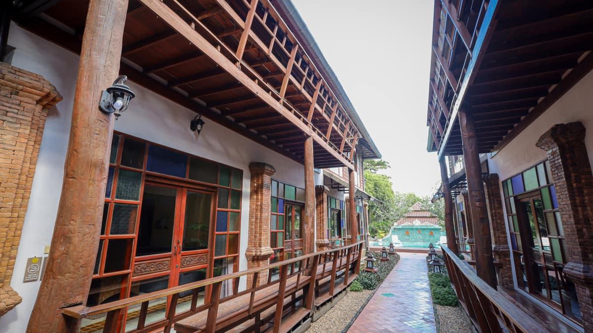 Ground-floor walkway with teak columns and lanterns at Jintara Rehab compound, Chiang Mai Thailand