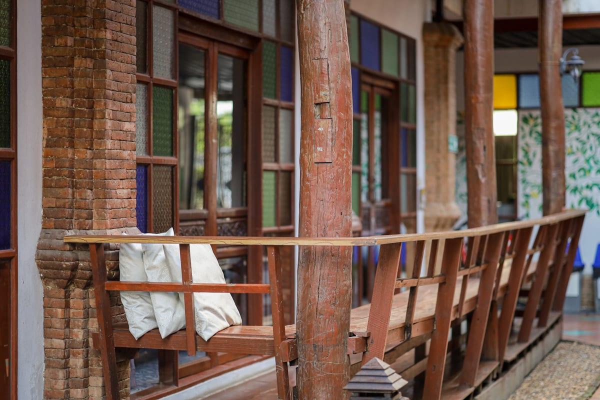 Teak veranda with brick columns and stained glass at Jintara Rehab outside Chiang Mai