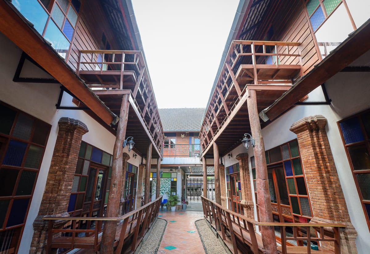 Teak walkways and brick columns along the central courtyard at Jintara Rehab outside Chiang Mai