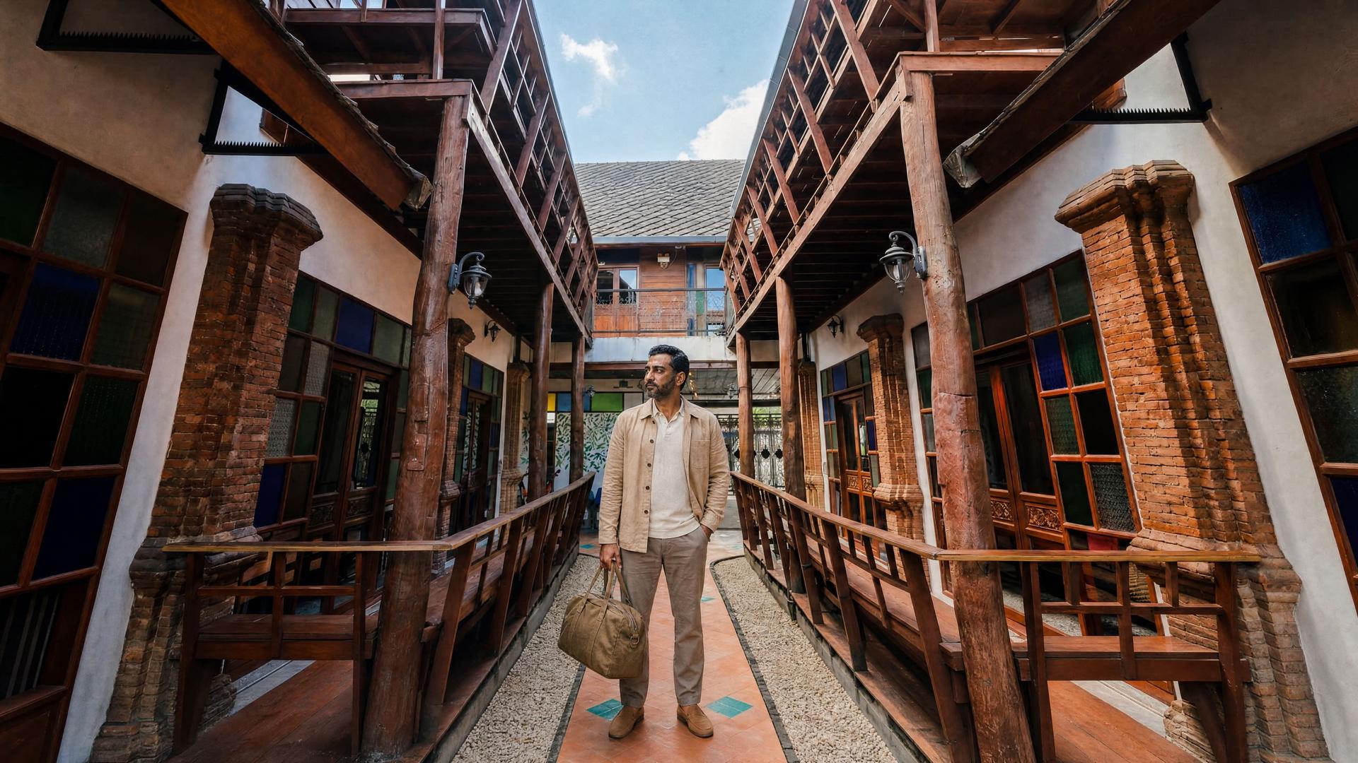 A man arriving with a bag in a teak courtyard at a residential rehab near Chiang Mai