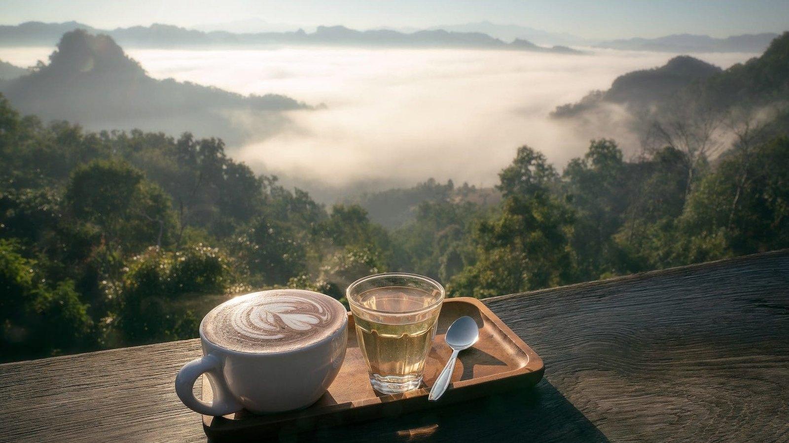 Coffee and tea on a wooden rail above a mist-filled valley in the mountains outside Chiang Mai