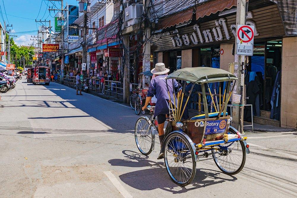 An ordinary weekday street in the old city of Chiang Mai, with a cycle rickshaw and shopfronts