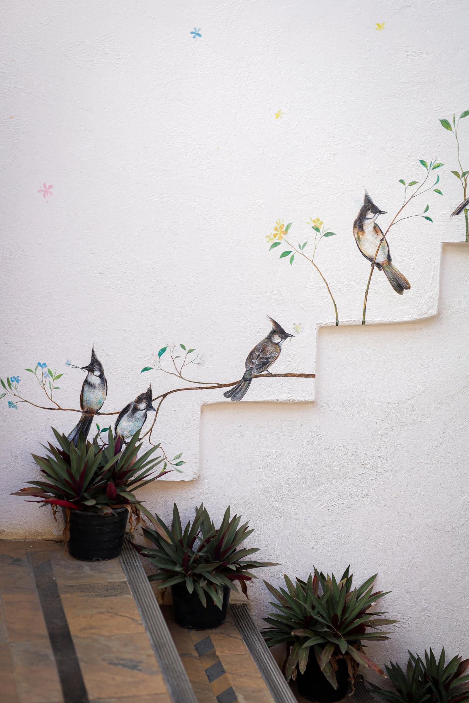 White staircase with hand-painted bird mural and potted plants at Jintara Rehab Chiang Mai