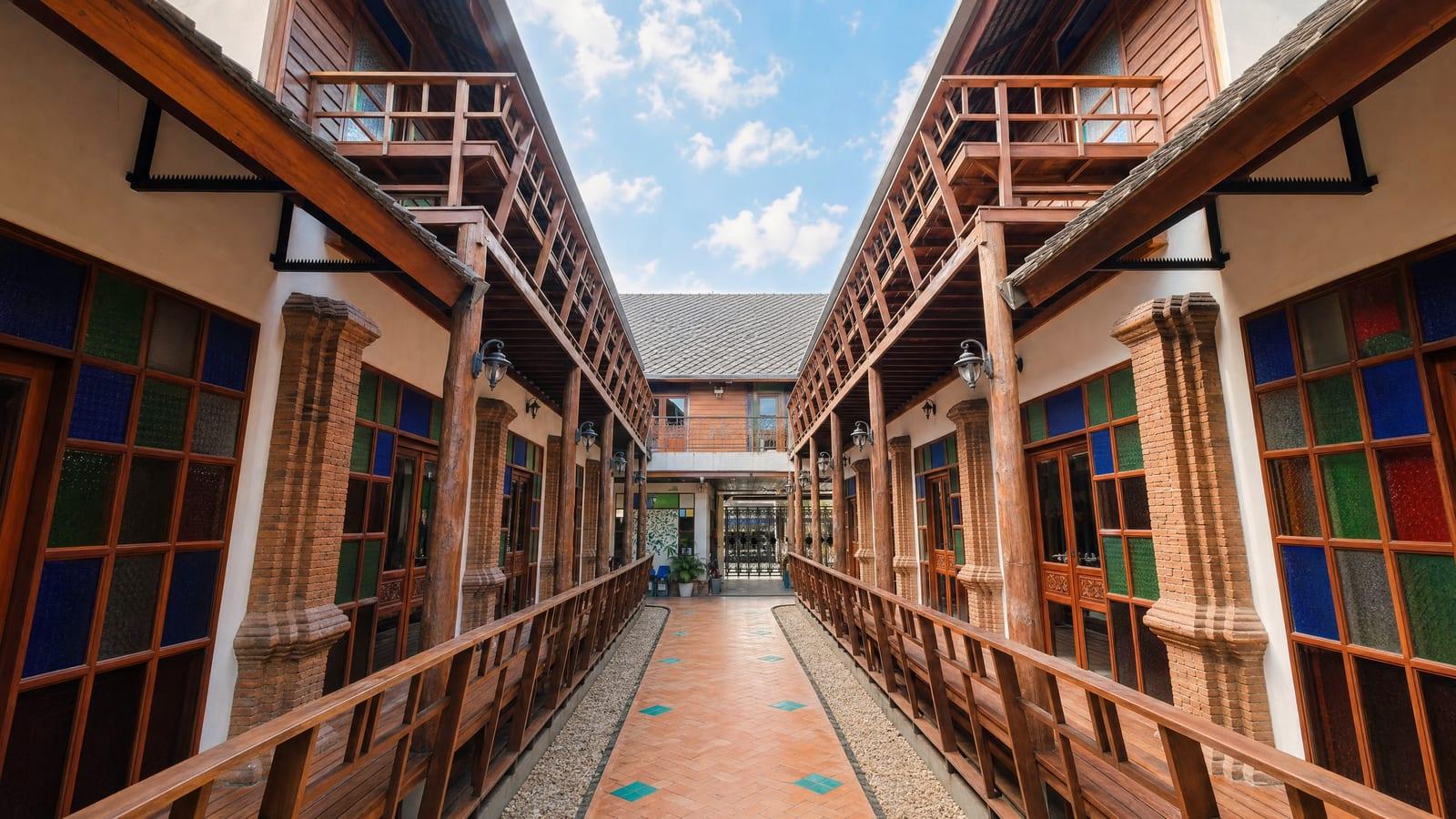 Lanna timber building with stained glass and tropical garden in bright daylight at Jintara Rehab Chiang Mai Thailand