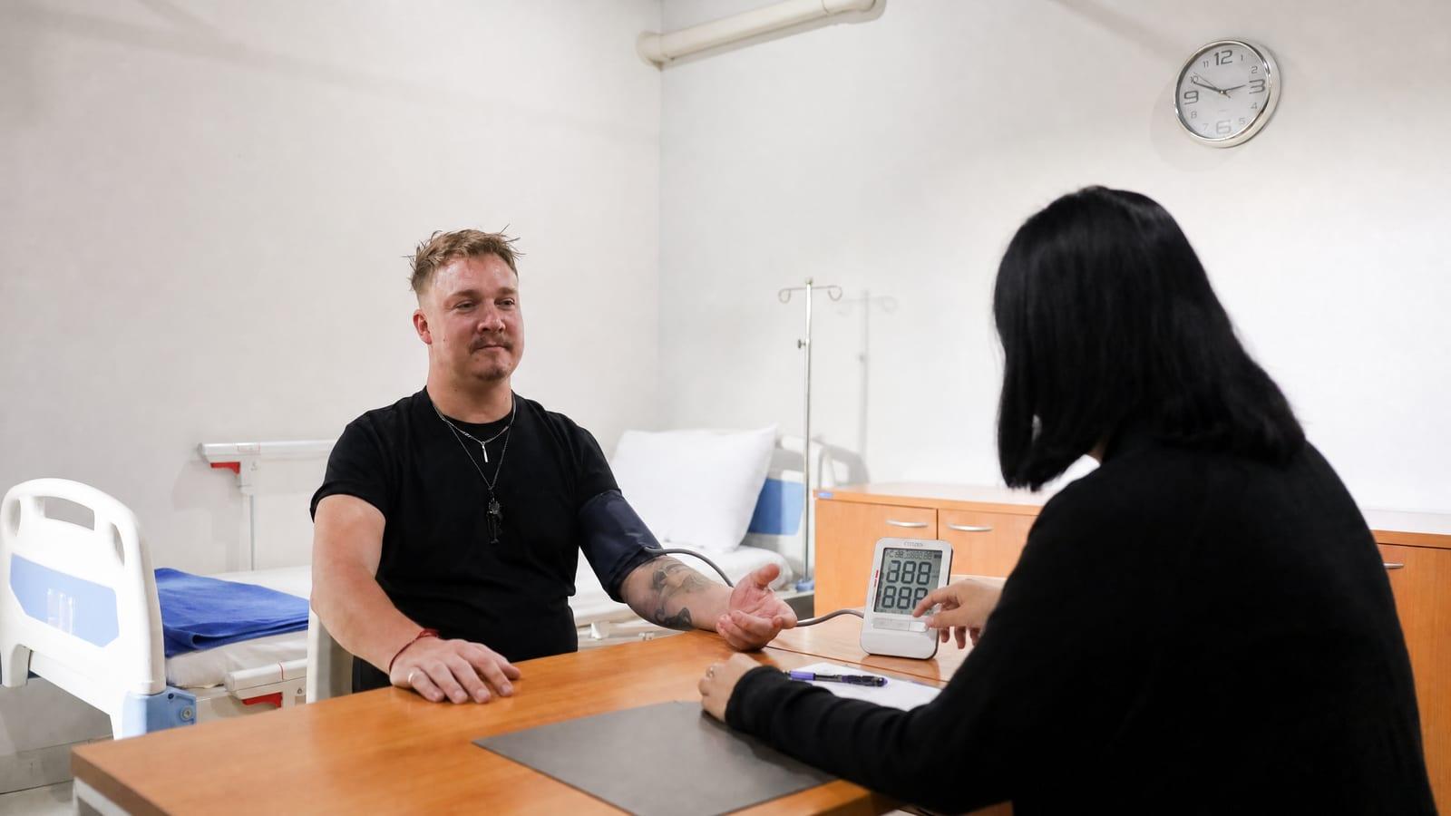 Nurse taking a male client's blood pressure with monitor reading visible in the clinical room at Jintara Rehab Thailand for cardiac monitoring during cocaethylene detox