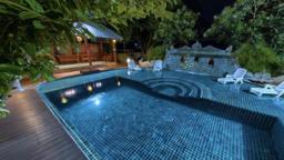 Lit swimming pool and timber sala in the evening grounds at Jintara Rehab Chiang Mai Thailand