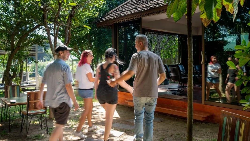 Clients walking together through tropical grounds towards a pavilion at a Chiang Mai rehab