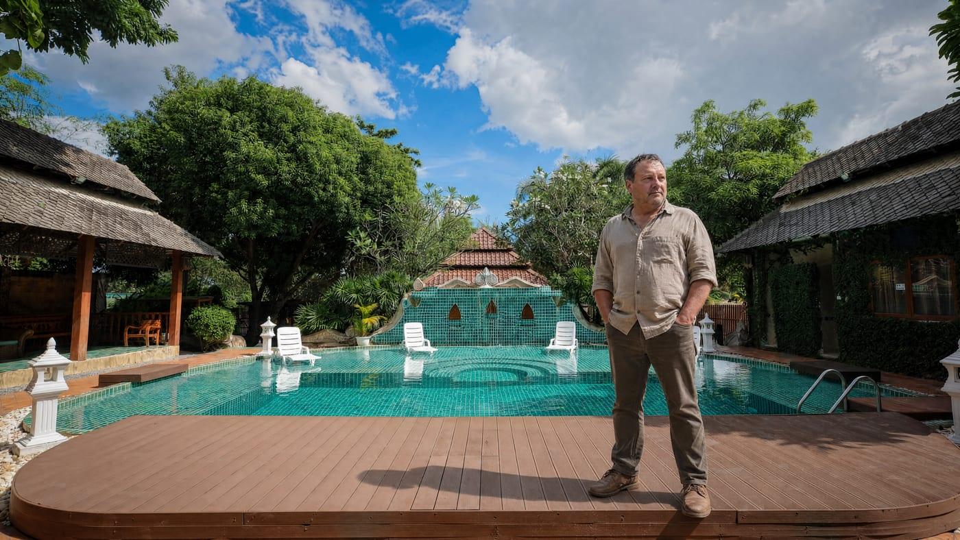 Man standing calmly by the pool at Jintara Rehab Chiang Mai where depression and addiction are treated together