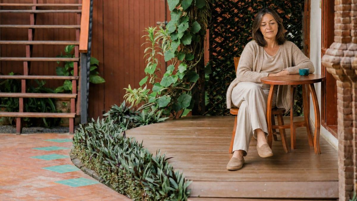 A woman sits calmly at a courtyard table in the residential setting at Jintara Rehab Chiang Mai