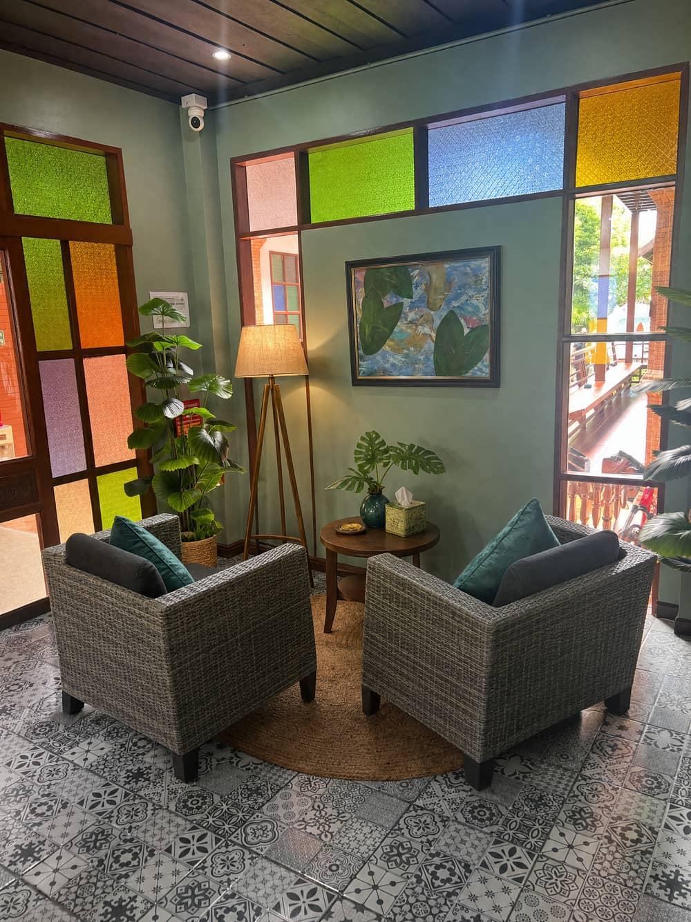 Rattan armchairs in the colorful stained-glass lounge at Jintara Rehab Chiang Mai