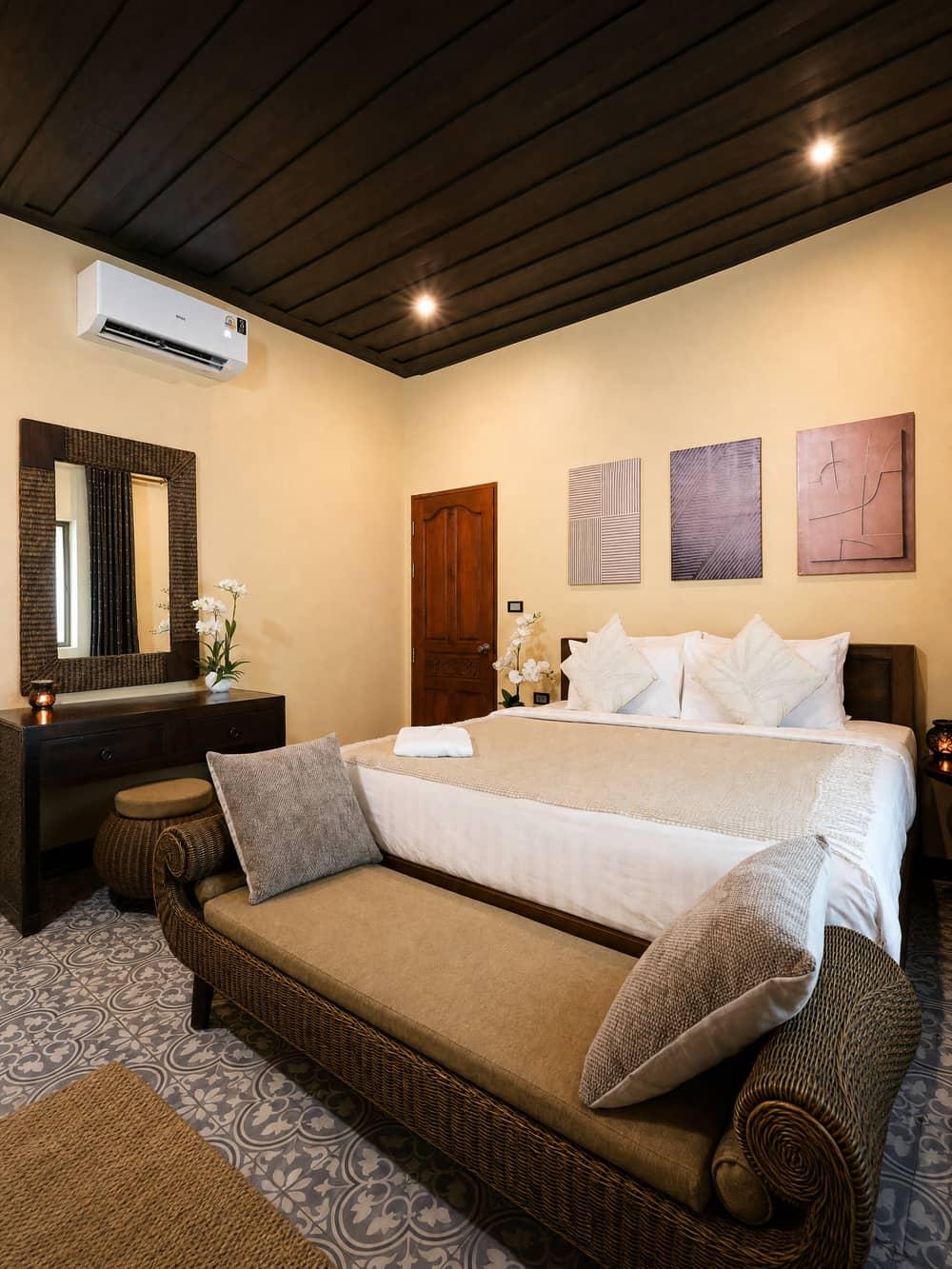 Private king bedroom with wicker furniture and dark wood ceiling at Jintara Rehab Chiang Mai