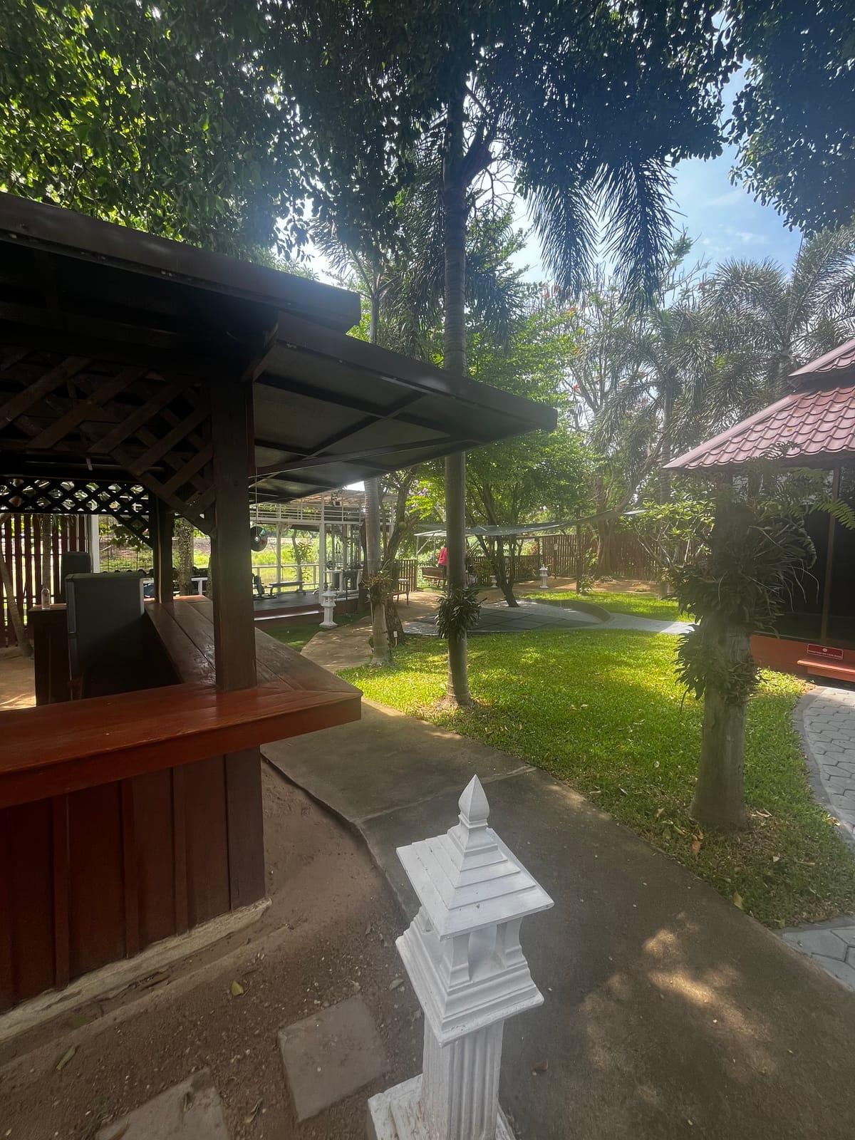 A paved path past a garden sala, lawn and a white stone lantern at Jintara Rehab in Chiang Mai, photographed by a Google reviewer