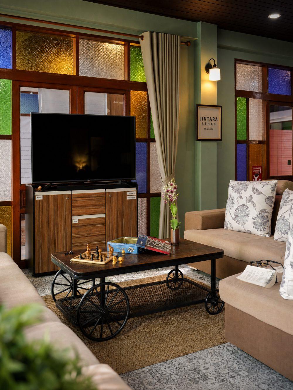 Interior lounge with chess set and stained glass window at Jintara Rehab, Chiang Mai
