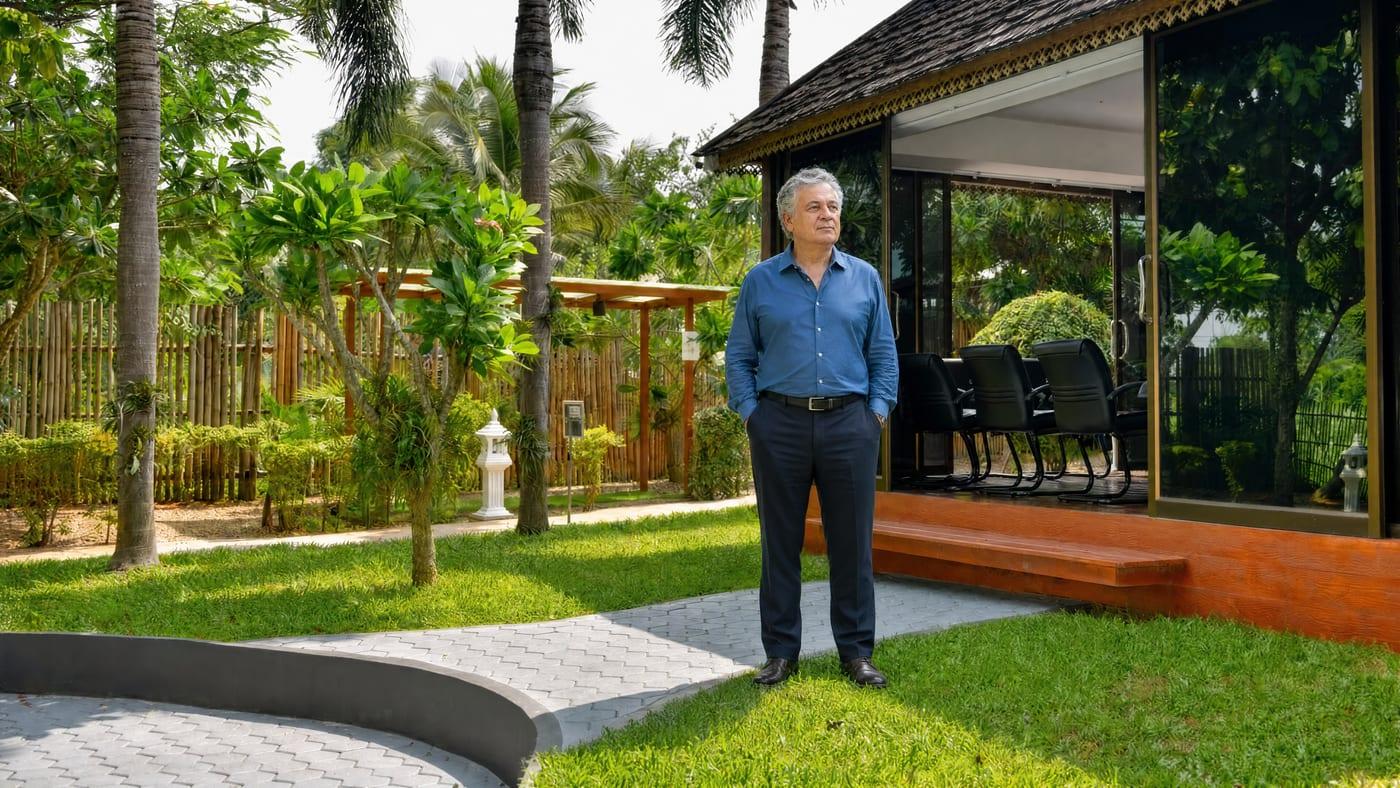 Older man standing on the garden lawn by the glass pavilion at Jintara Rehab Chiang Mai