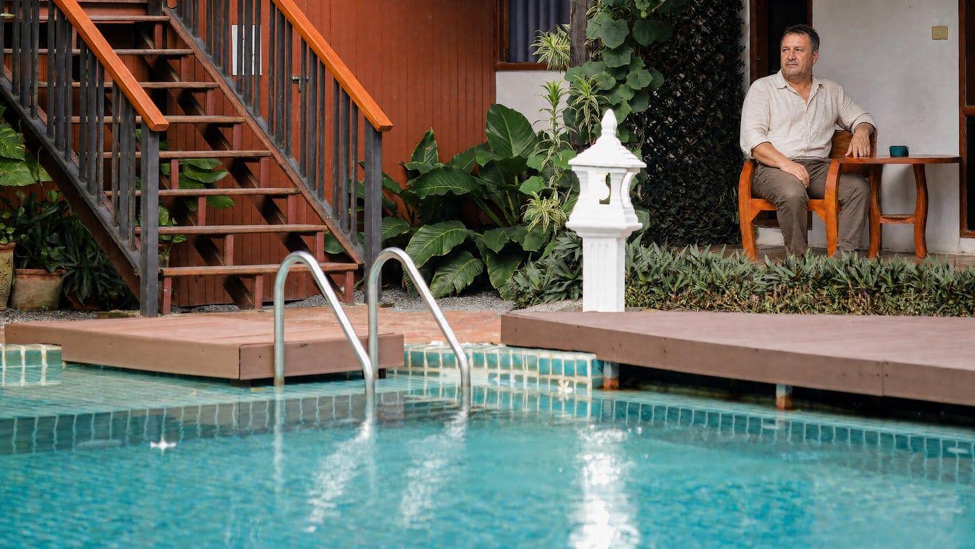 A man sitting calmly by the pool at the Jintara Rehab facility in Chiang Mai