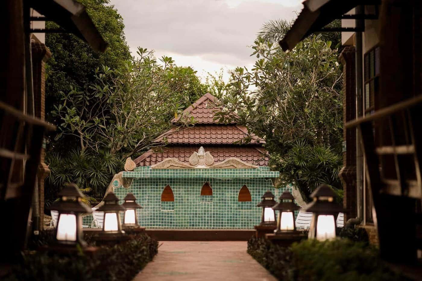 Lantern-lit walkway at Jintara Rehab in Chiang Mai leading to a teal pavilion at dusk