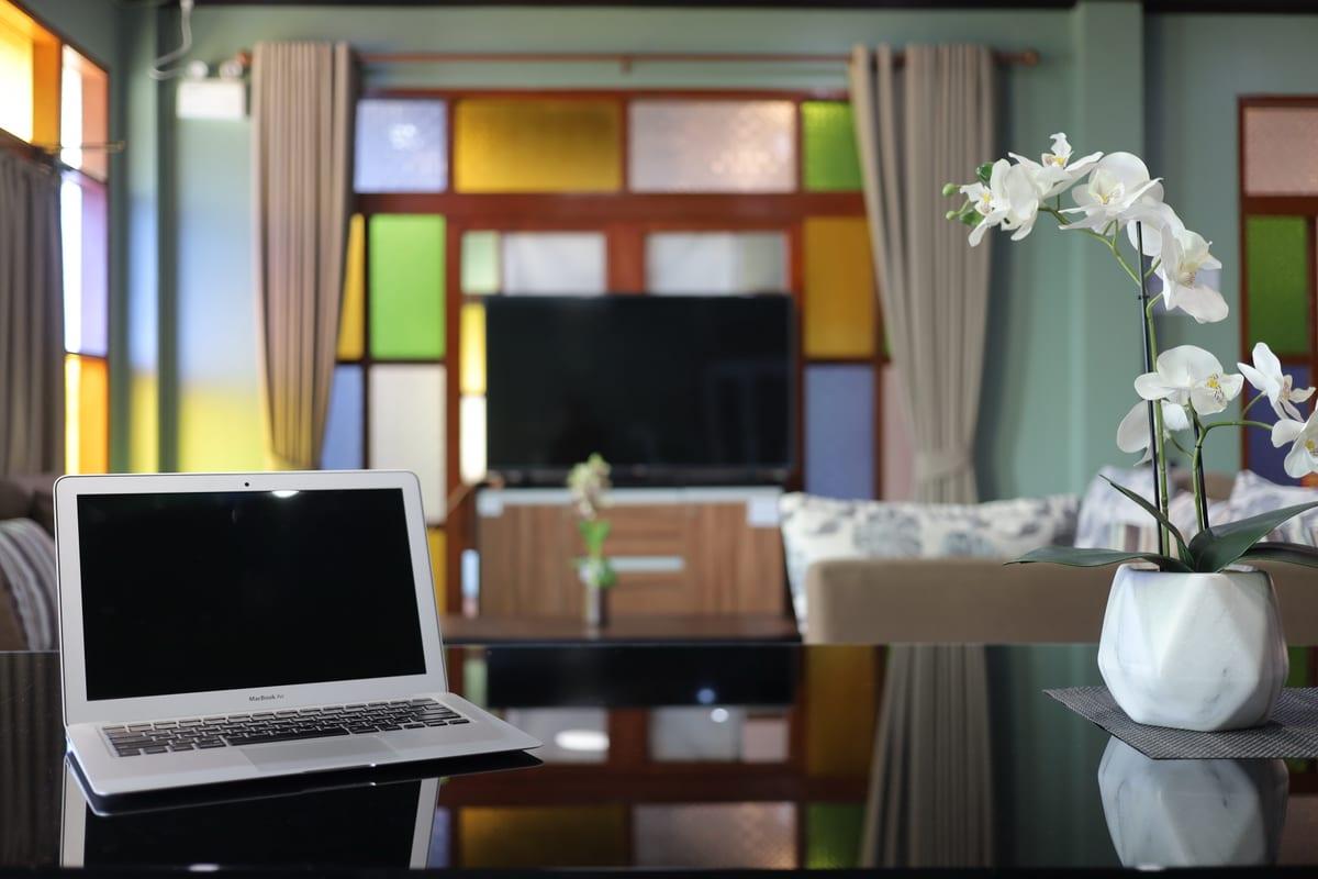 Laptop and orchid on a table in a private lounge at Jintara Rehab with colourful stained glass windows