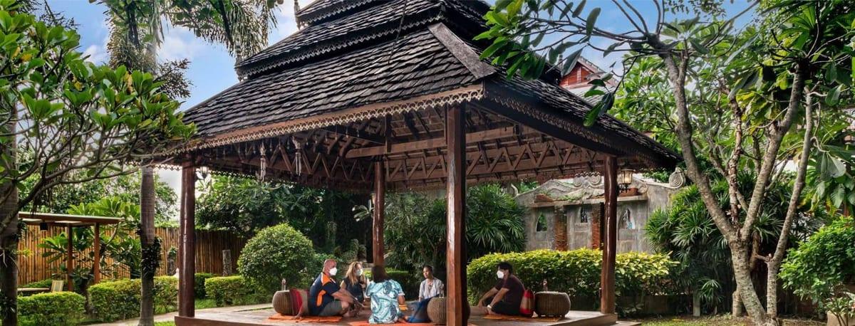 Traditional Lanna sala with group of individuals in tropical grounds at Jintara Rehab Chiang Mai