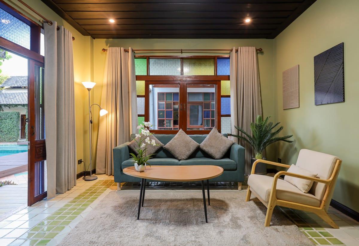 Communal lounge at Jintara Rehab with teal sofa, coffee table, and glass doors opening to pool area