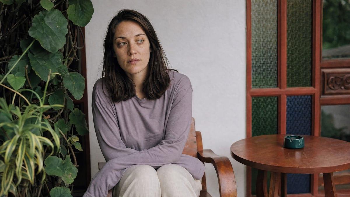 A woman sits quietly on a timber veranda chair in the early days of detox at a Chiang Mai rehab