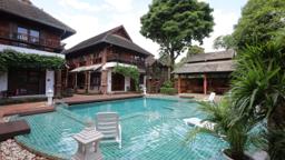 Teal-tiled pool and Lanna teak buildings at Jintara Rehab in Chiang Mai Thailand