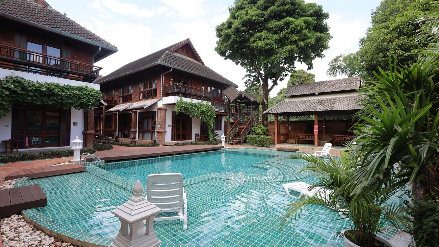 Teal-tiled pool and Lanna teak buildings at Jintara Rehab in Chiang Mai Thailand