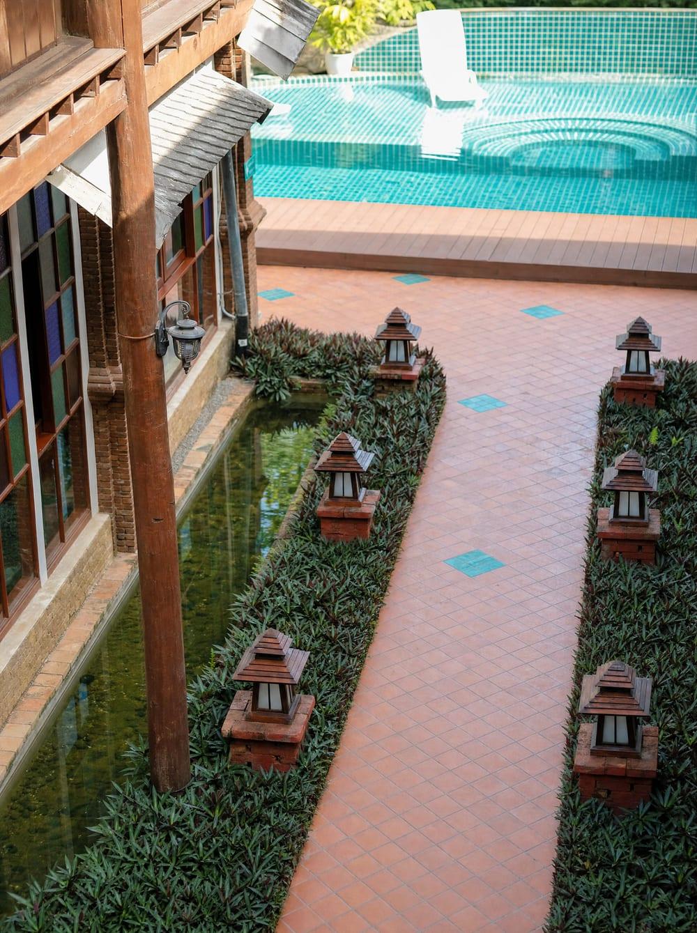 Pool courtyard with lanterns and teak building facade at kratom treatment centre Jintara Rehab Chiang Mai