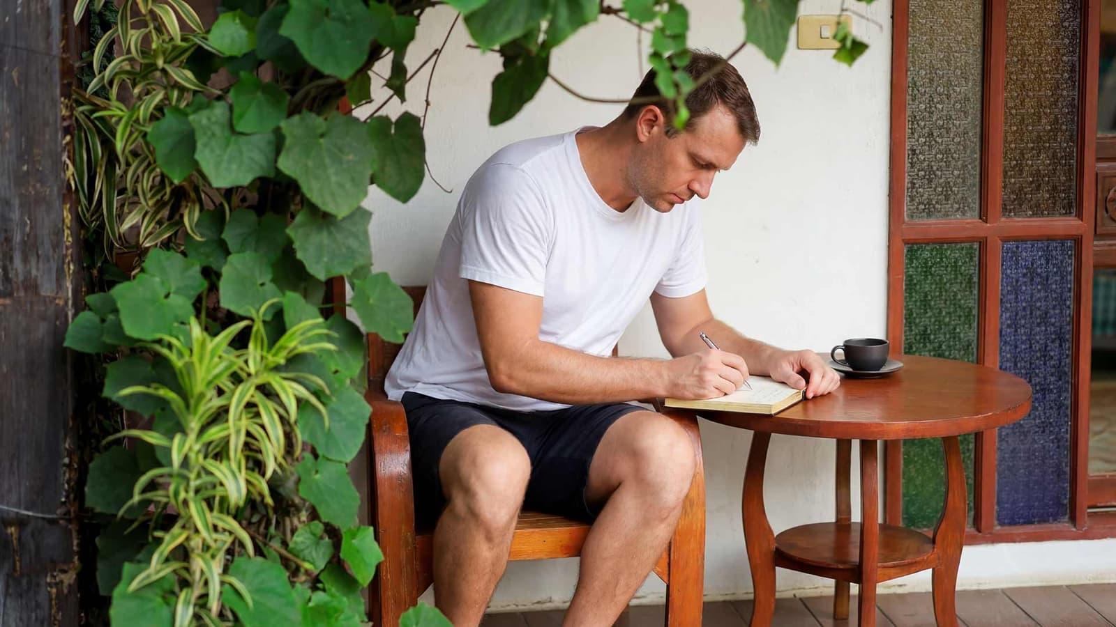 A client writing alone in a quiet corner of the grounds at Jintara Rehab in Chiang Mai