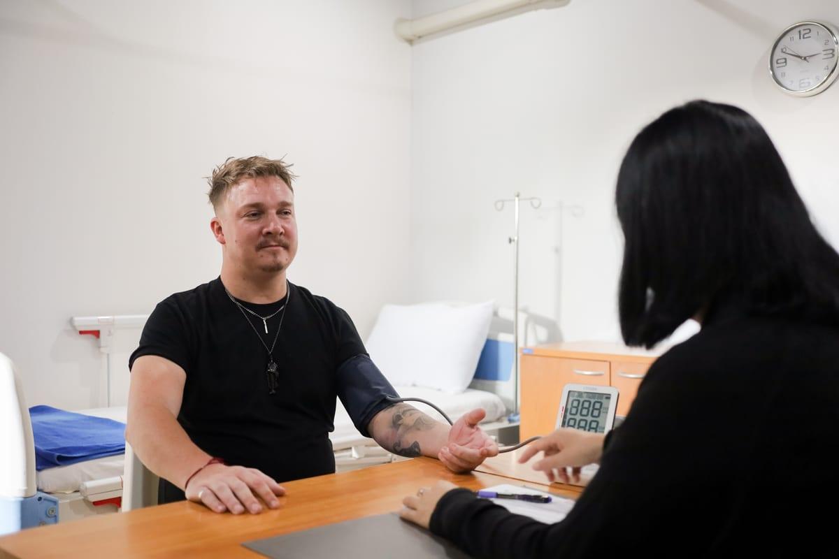 Nurse taking a blood pressure reading during alcohol withdrawal monitoring in a clinical room at Jintara Rehab Thailand