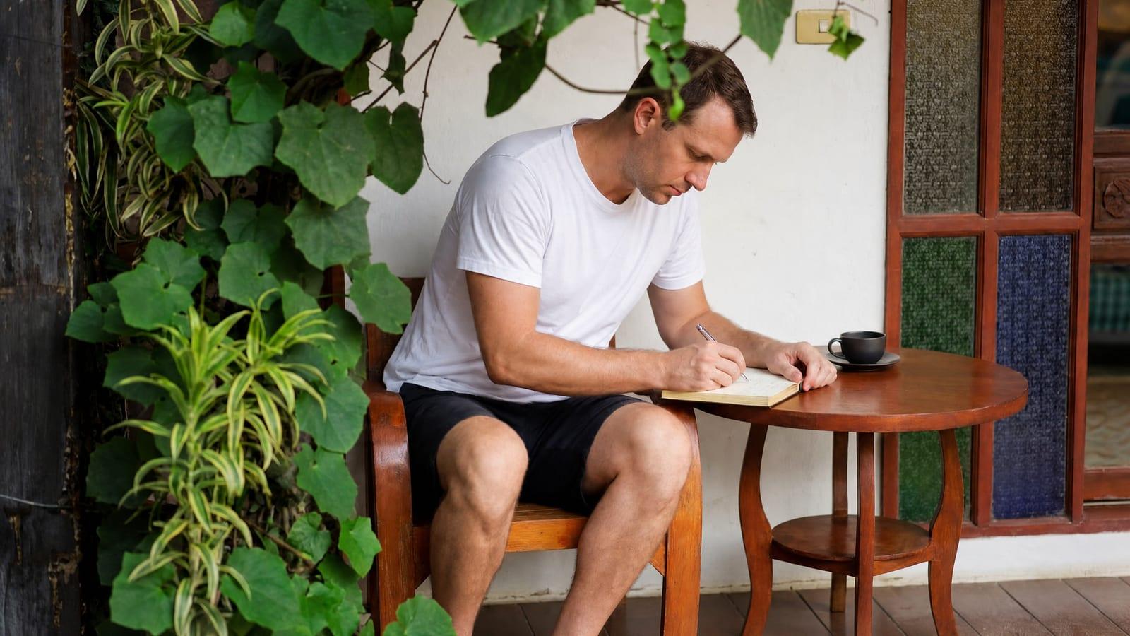 Person writing in journal in Jintara's garden during post-detox recovery in Chiang Mai