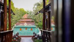 Private timber walkway framing the pool and Lanna pavilion at Jintara Rehab in Chiang Mai