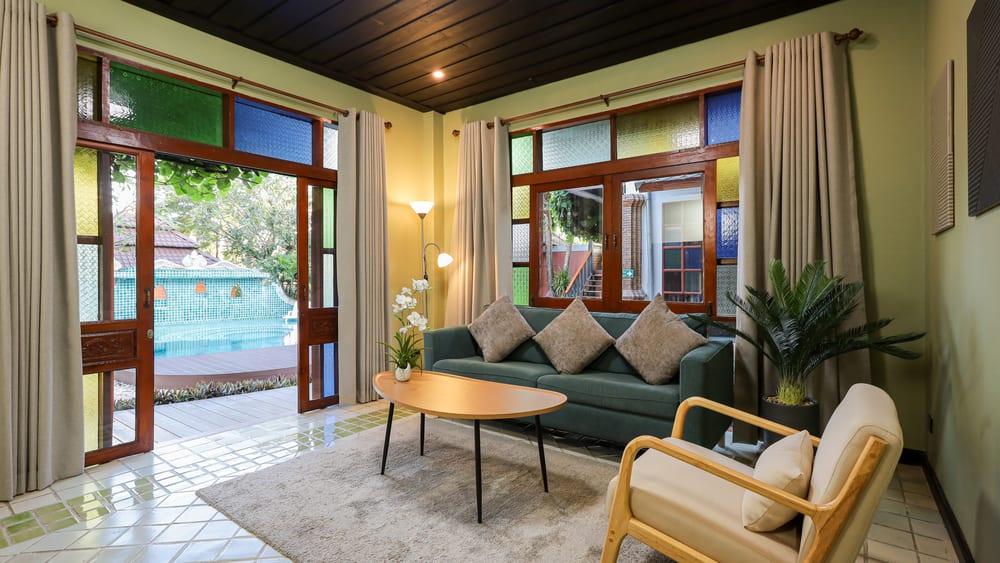 Bright residential lounge at Jintara Rehab Chiang Mai with teal sofa and pool view, showing the calm everyday environment where recovery begins