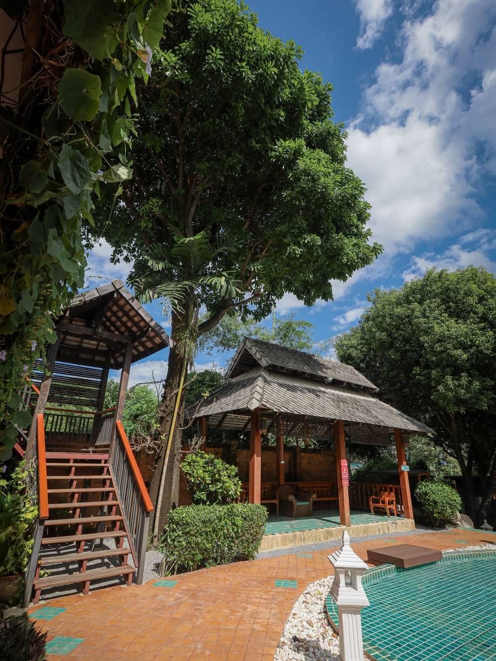 A quiet timber pavilion beside the pool in warm daylight at Jintara Rehab in Chiang Mai Thailand