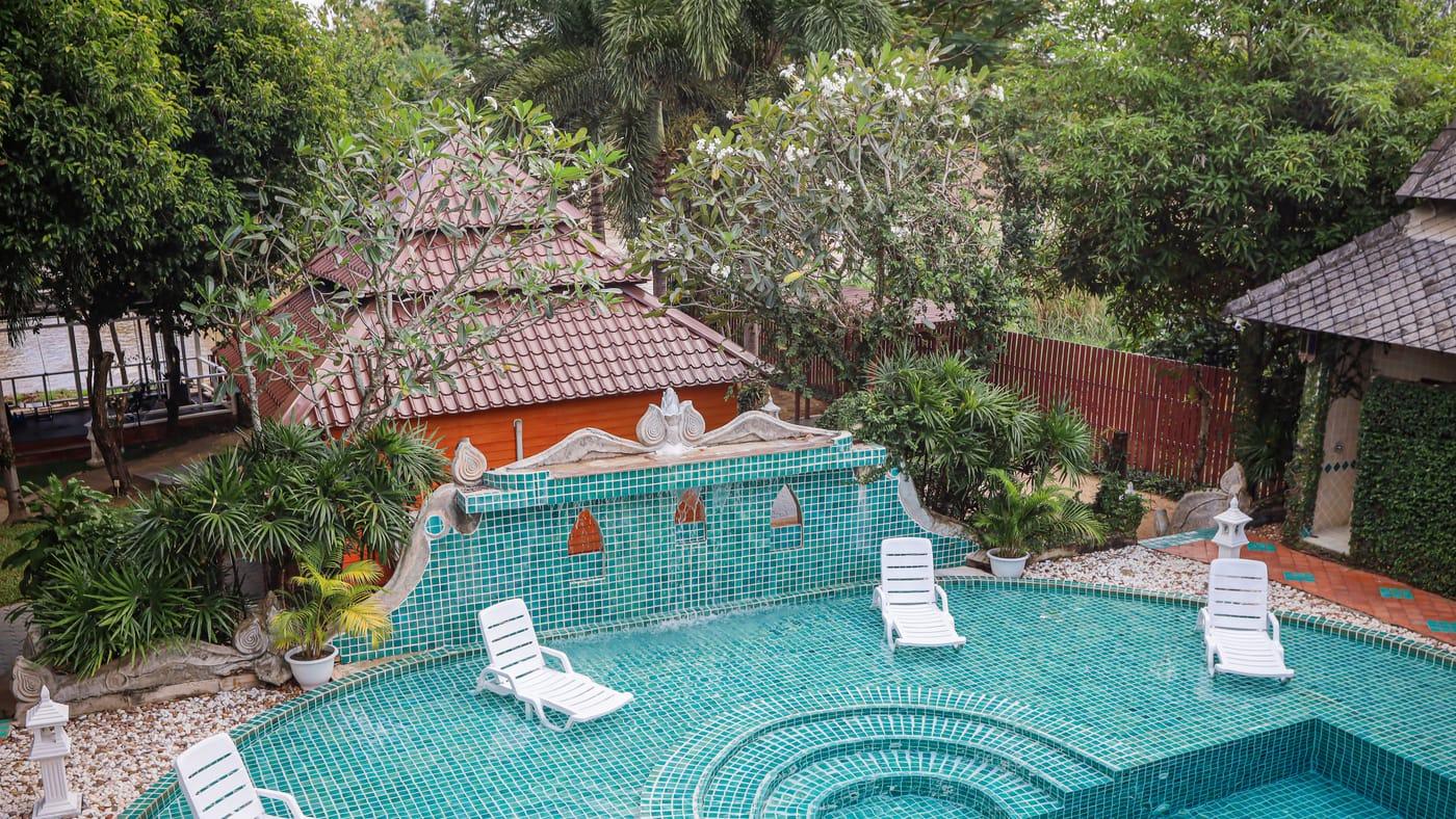 The pool and garden at Jintara Rehab in Chiang Mai, with loungers in the shallow water and a tiled fountain wall