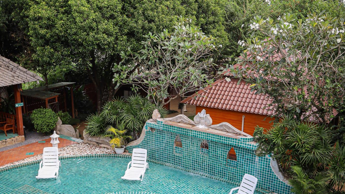 Elevated view of the tiled pool, white loungers and trees at Jintara Rehab