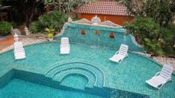 Pool with a tiled fountain wall and white loungers at Jintara Rehab in Chiang Mai