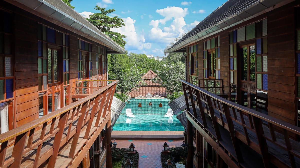 Two teak buildings with balconies facing the pool at Jintara Rehab in Chiang Mai