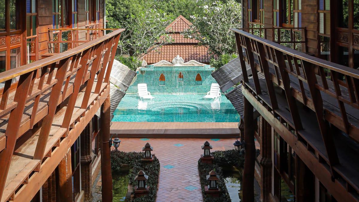 The view from a teak balcony down a lantern-lined walkway to the tiled fountain pool at Jintara Rehab in Chiang Mai