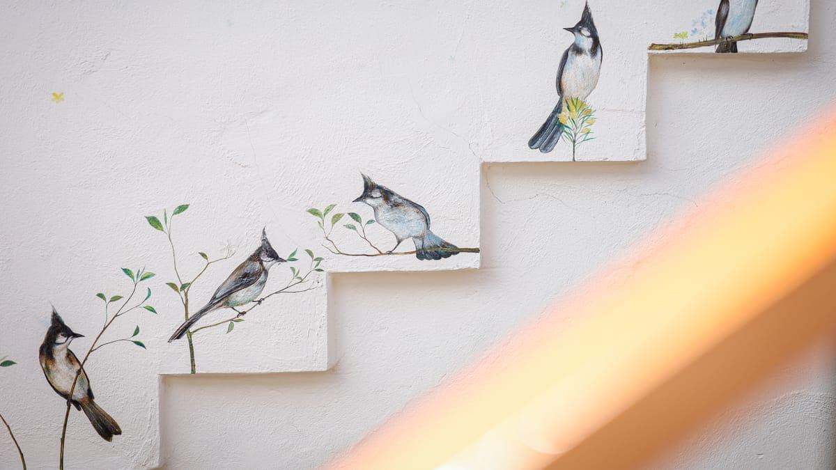 Birds painted along a stepped white wall at Jintara Rehab in Chiang Mai