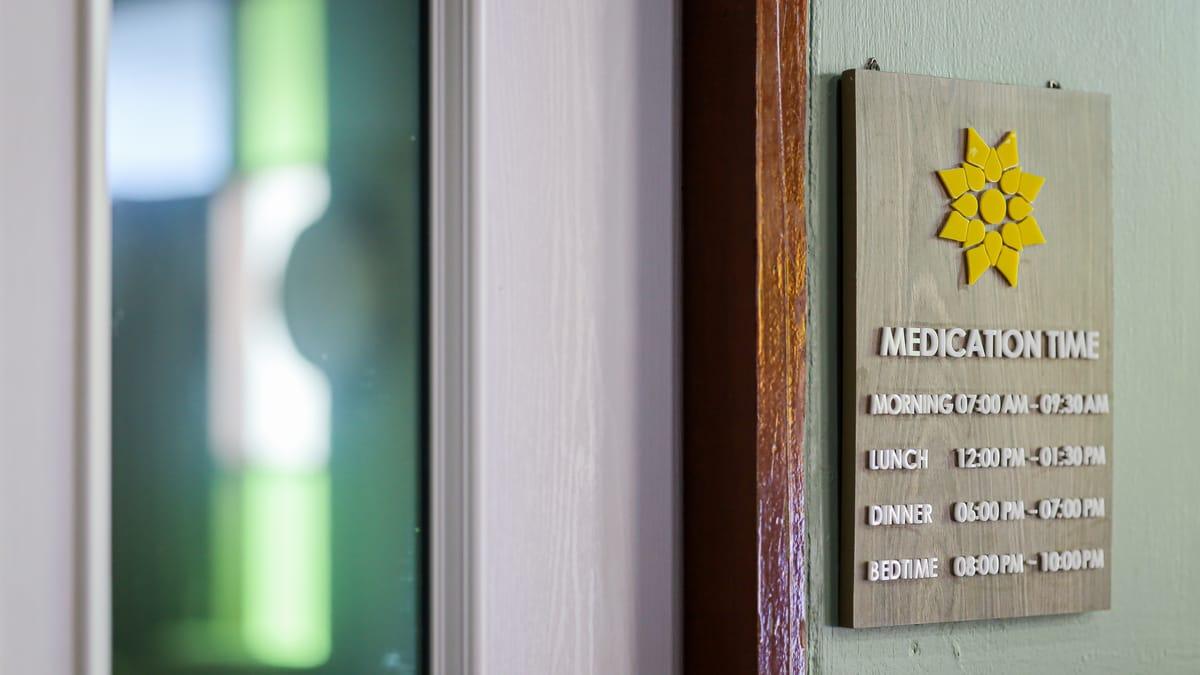 Medication time sign listing morning, lunch, dinner and bedtime hours at Jintara Rehab in Chiang Mai