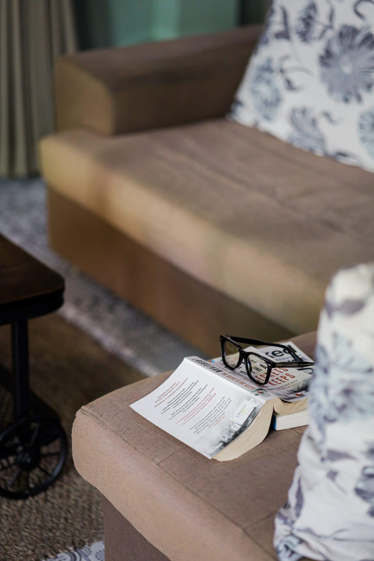 Reading glasses and an open book on a sofa in a lounge at Jintara Rehab in Chiang Mai