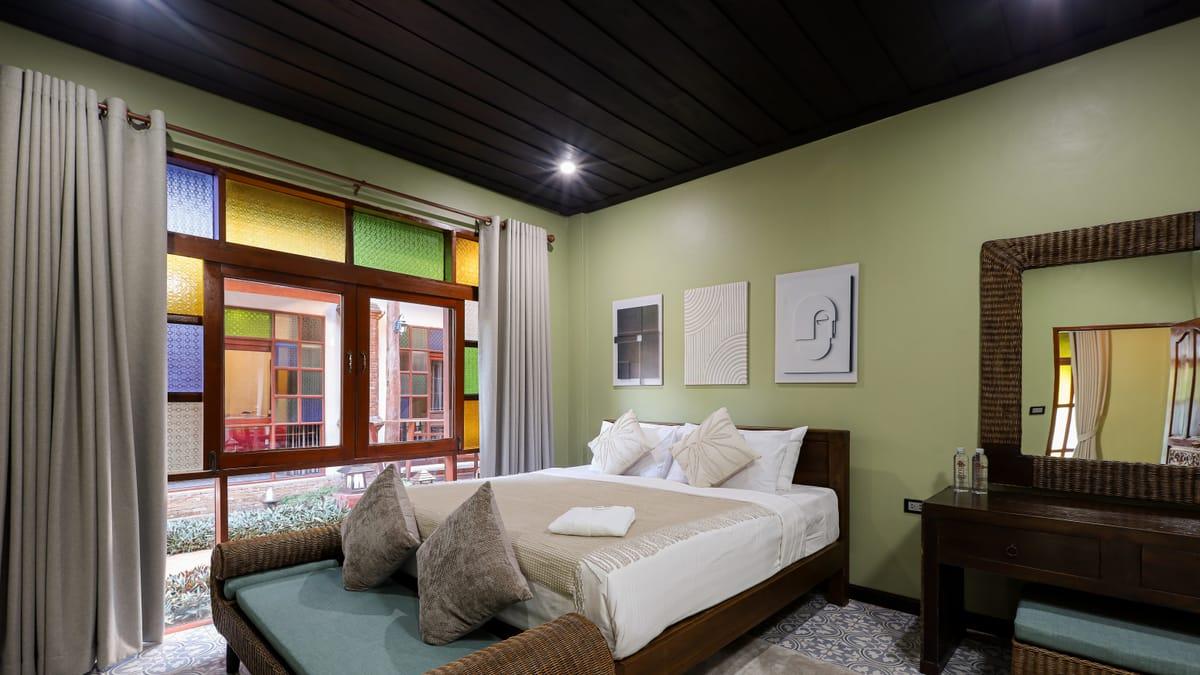 A bedroom with a double bed and stained glass windows at Jintara Rehab in Chiang Mai