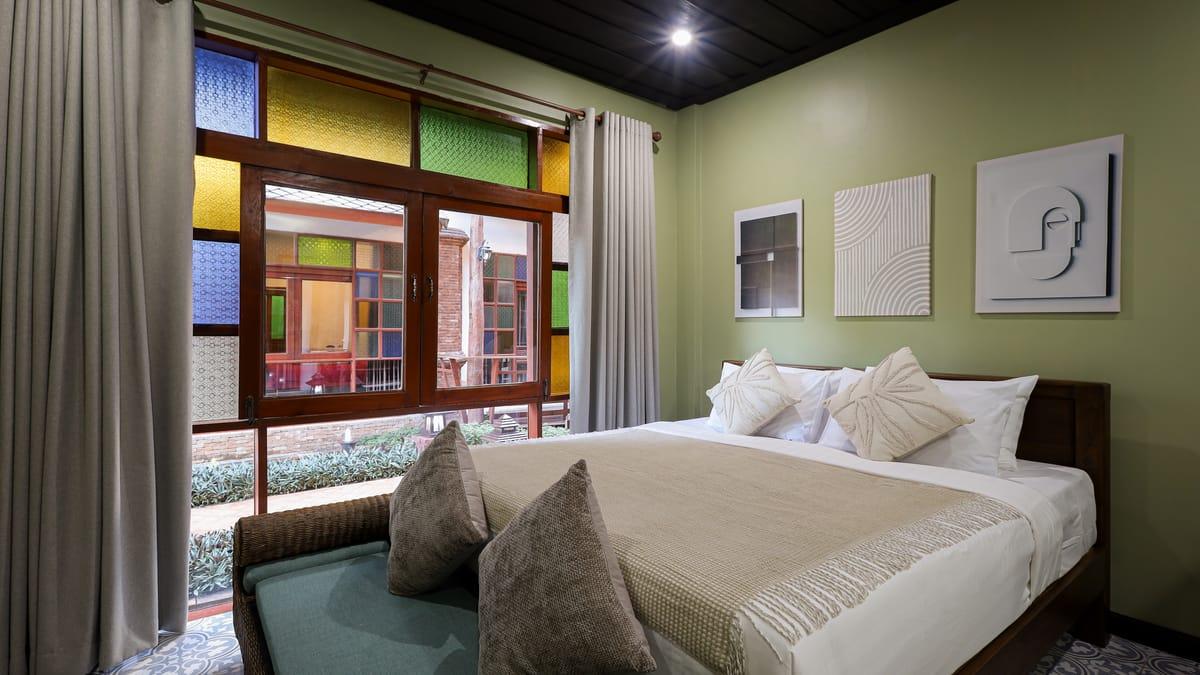 A bedroom with stained-glass windows looking onto the garden at Jintara Rehab in Chiang Mai