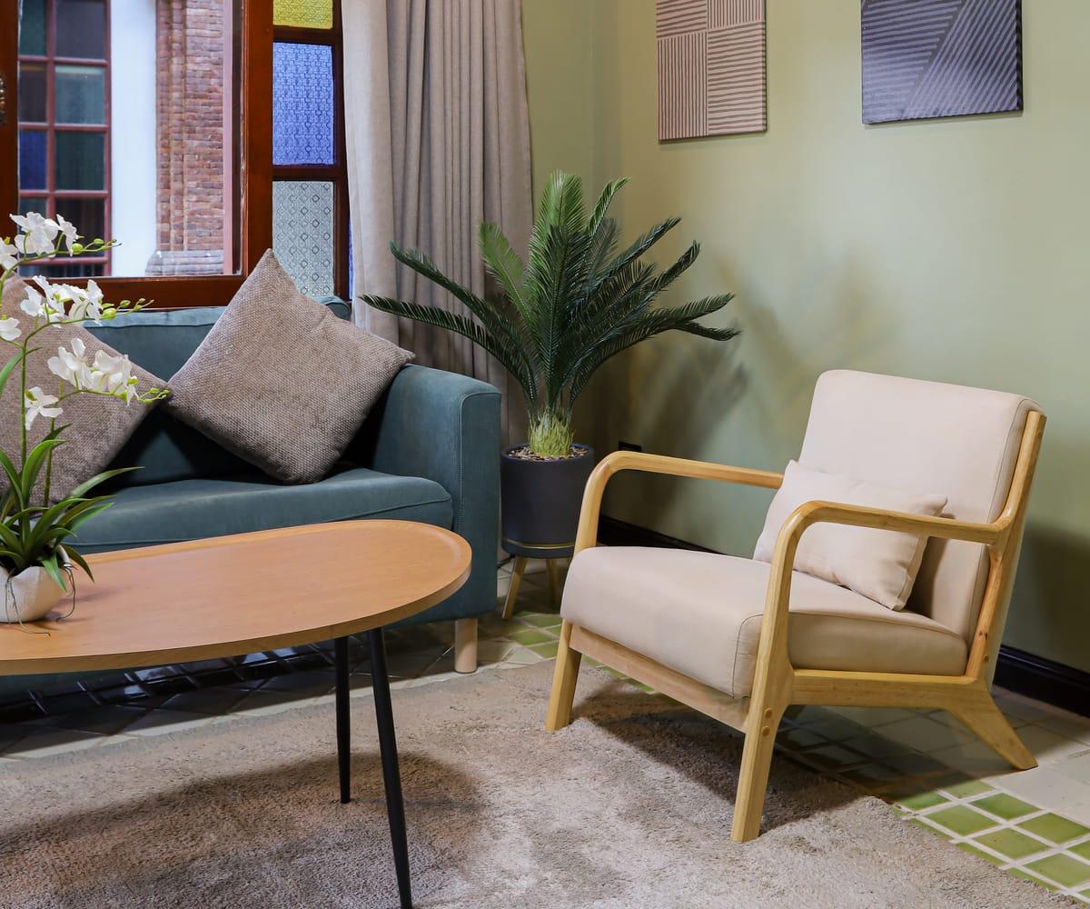 An armchair, sofa and potted palm in a lounge corner at Jintara Rehab in Chiang Mai
