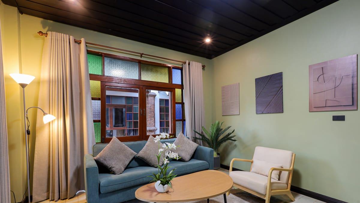 A lounge with a sofa, armchair and stained glass windows at Jintara Rehab in Chiang Mai
