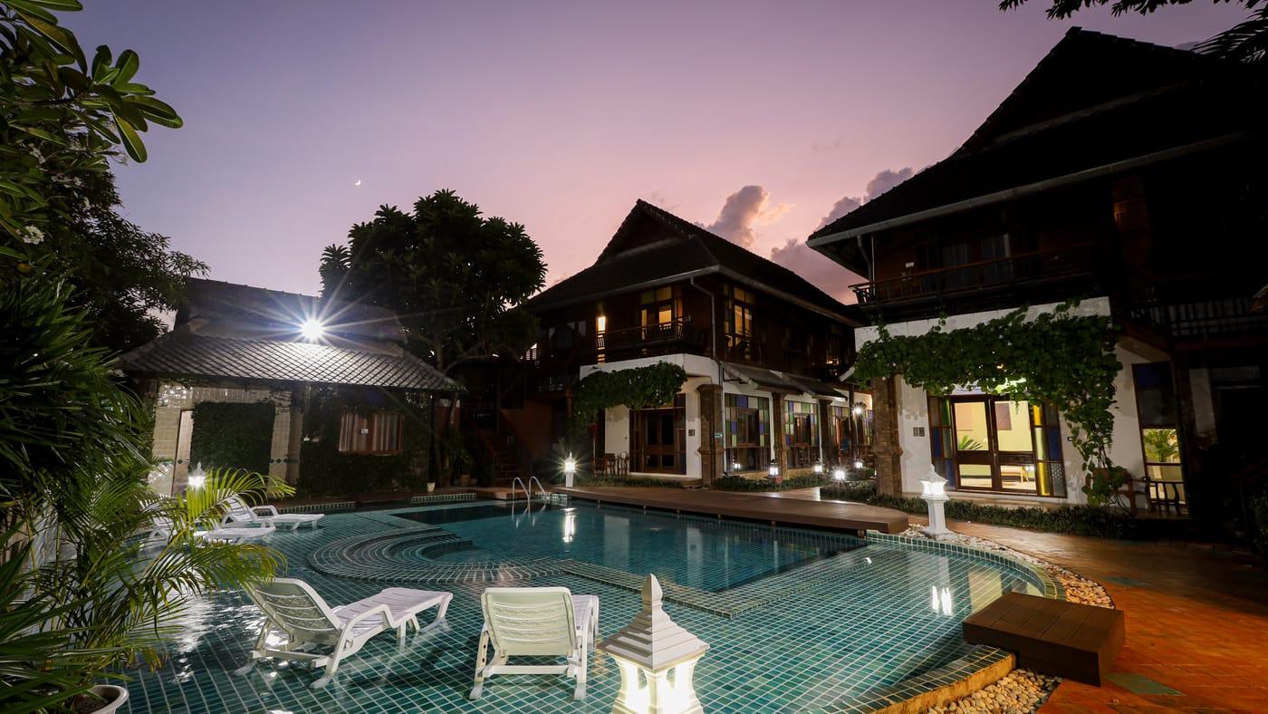 The pool and teak buildings at dusk at Jintara Rehab in Chiang Mai